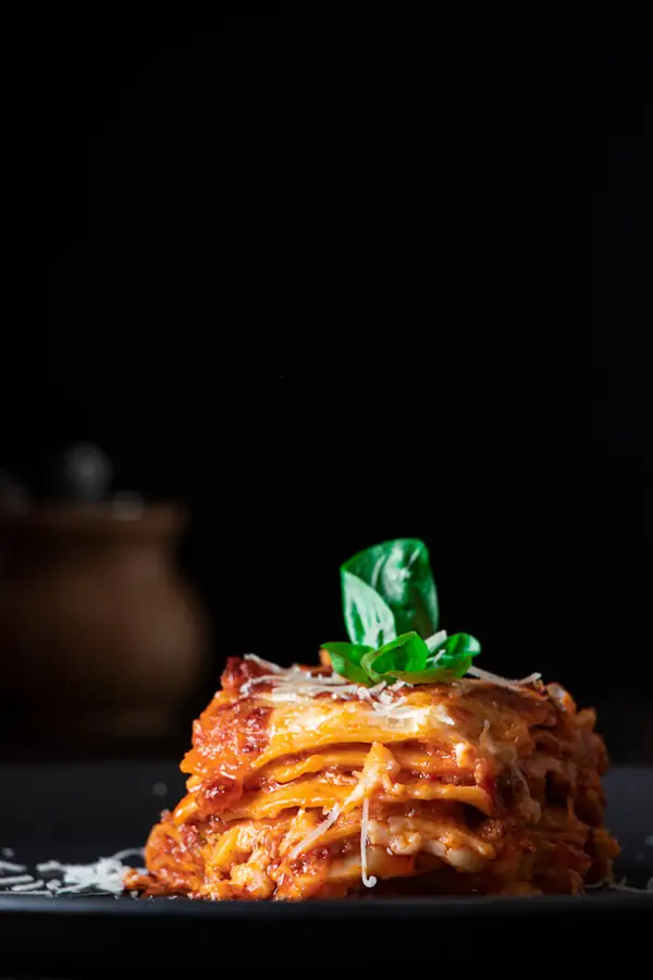 Lasagne auf einem dunklen Teller (Serviervorschlag)